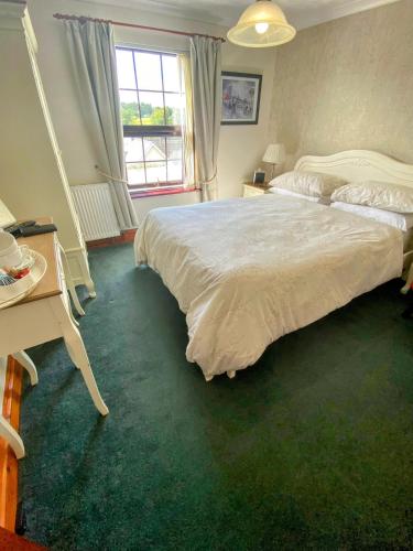 a bedroom with a bed and a desk and a window at Flambards Hotel in Cardigan