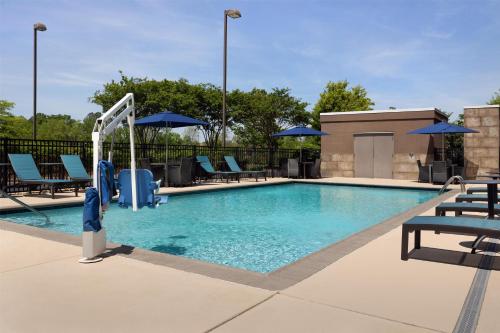 a swimming pool with chairs and umbrellas at Home2 Suites by Hilton Huntsville Research Park Area, AL in Huntsville