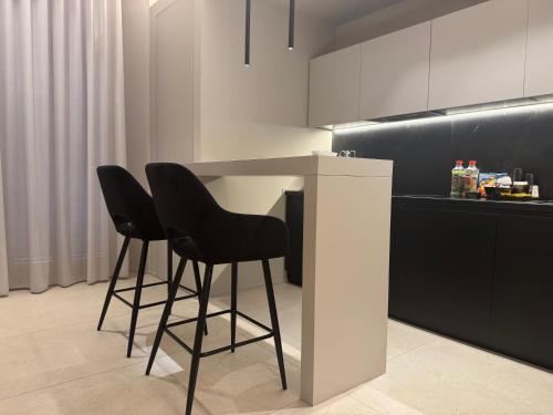 a kitchen with two black chairs and a table at Virginia Madre Luxury Rooms in San Benedetto del Tronto