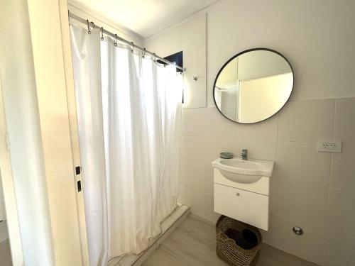 ein Badezimmer mit einem weißen Duschvorhang und einem Spiegel in der Unterkunft Casa Laura - Casa en Chapa zona Cruz del Sur para 5 PAX - Hola Sur in Chapadmalal
