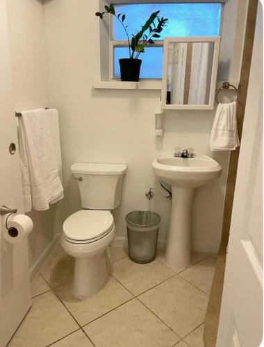 a bathroom with a toilet and a sink and a window at Florida Charm in Pompano Beach