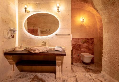 a bathroom with a sink and a mirror and a toilet at Lagoon Cave Suites in Urgup