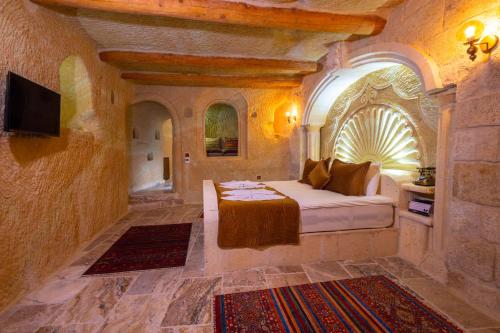 a bedroom with a bed in a stone room with a tv at Lagoon Cave Suites in Urgup