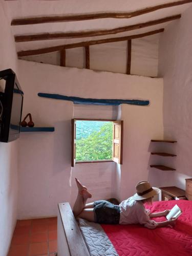 a person laying on a bed in a room with a window at San Rafael del Campo - Barichara in Barichara