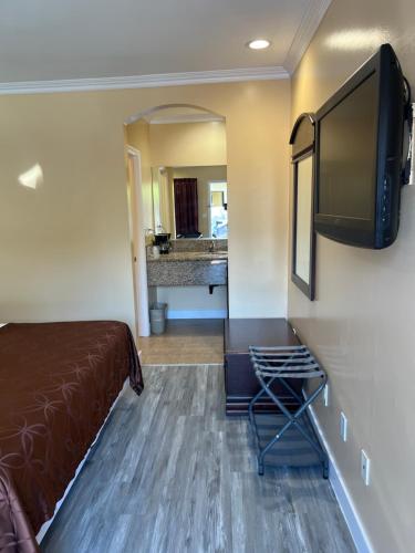 a hotel room with a bed and a flat screen tv at Carlton Motor Lodge in Los Angeles