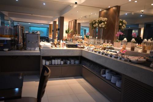 a restaurant with a counter with food on it at Master Gold Hotel Express in Cascavel