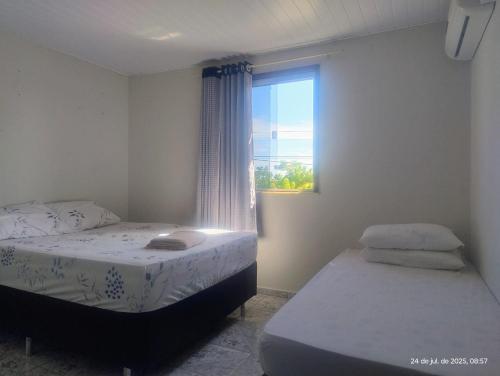 ein Schlafzimmer mit zwei Betten und einem Fenster in der Unterkunft hostel xamã in Flecheiras