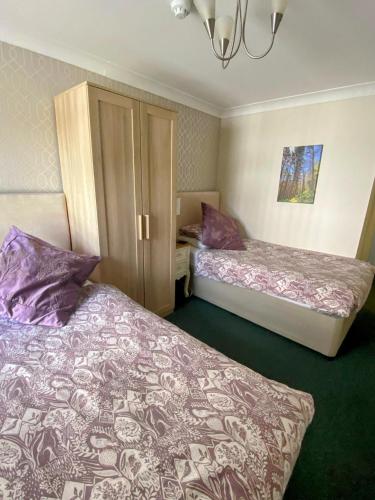two beds in a small room with purple pillows at Flambards Hotel in Cardigan