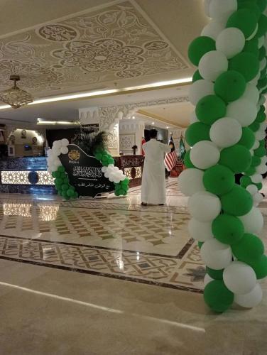 a bride and groom walking down a dance floor with green and white balloons at راجان للشقق المخدومة in Taif