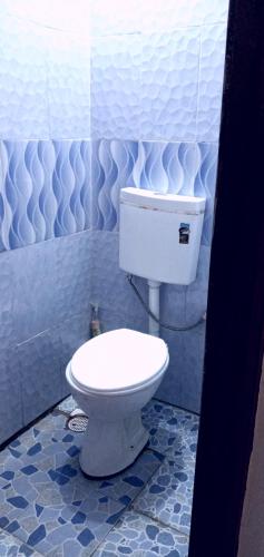 a bathroom with a toilet and a blue tiled wall at Royalcarevillas in Thika