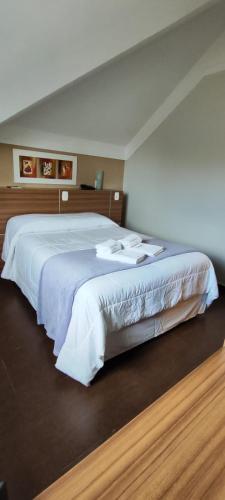 a bedroom with a large bed with white sheets at Hotel Aguadero in Passo Fundo