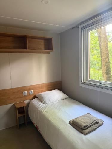 a small bedroom with a bed and a window at Mobil home B1Bis La Pointe LB in Capbreton