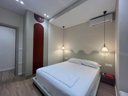 a bedroom with a white bed and two lights at BlueNest1 in Sarandë