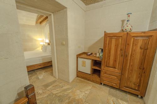 a small room with a bed and a wooden cabinet at Zara Cave Hotel in Goreme