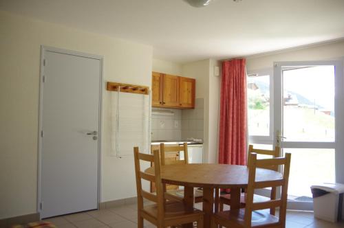 a kitchen with a wooden table and chairs and a door at CIS-Ethic Etapes de Val Cenis in Lanslebourg-Mont-Cenis