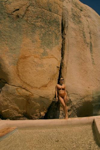 a woman in a bathing suit standing in a rock at Banyan Tree Veya, Valle de Guadalupe - A Wellbeing & Wine Resort in Valle de Guadalupe