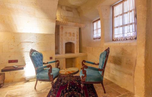 a room with two chairs and a table and a fireplace at Lagoon Cave Suites in Urgup