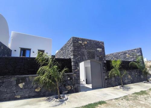 a stone house with a door in a wall at Koniko Santorini Private Pool Villas in Santorini