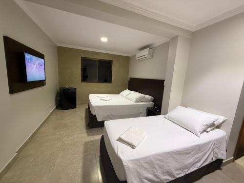 a hotel room with two beds and a flat screen tv at Master Gold Hotel Express in Cascavel