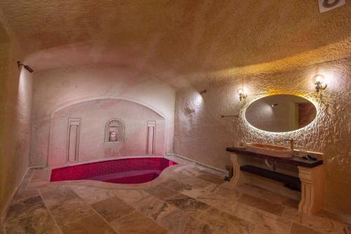 a bathroom with a red tub and a mirror at Lagoon Cave Suites in Urgup