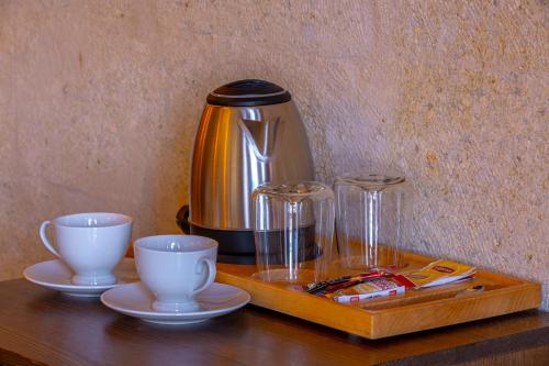 a coffee pot and two cups on a wooden table at Lagoon Cave Suites in Urgup