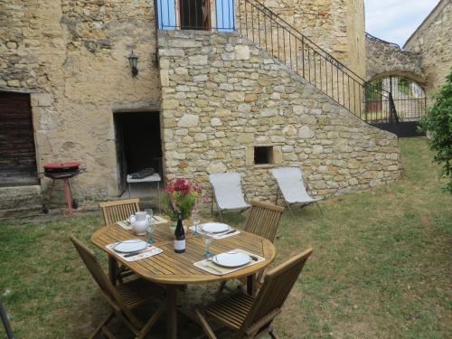 a wooden table and chairs in front of a stone building at Le Mas des Restanques in Le Poët-Laval