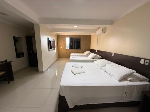 three beds in a hotel room with white sheets at Master Gold Hotel Express in Cascavel