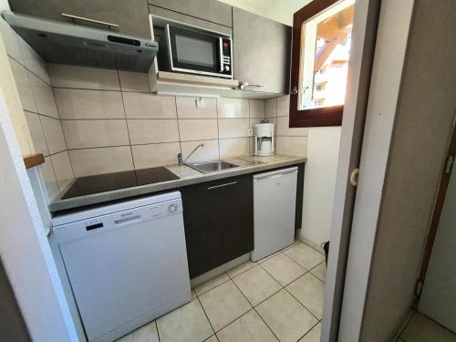 une petite cuisine avec un évier et un micro-ondes dans l'établissement Chalets Jardin Alpin - Chalet mitoyen lumineux · Accès pistes par navette · Wifi gratuit MAE-5014, à La Salle Les Alpes