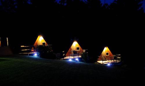 a group of three tents lit up at night at AirWood Glamping in Križe