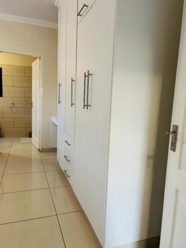 a bathroom with white cabinets and a tiled floor at Nurtured Stay's in Manzini