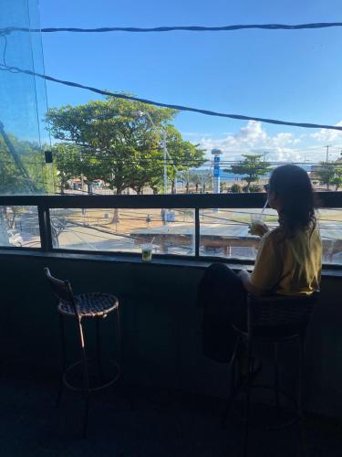 a woman sitting in a chair looking out a window at Hostel do Meio in Salvador