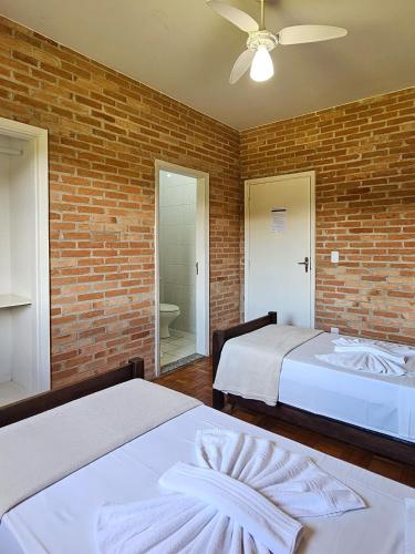 a bedroom with two beds and a brick wall at Siloe Hotel by Concavus in Vinhedo
