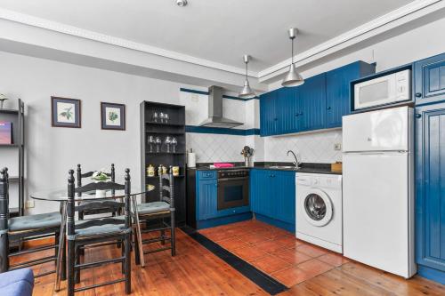 a kitchen with blue cabinets and a table and a dishwasher at Apartamentos San Roque en Llanes by megustarural in Llanes