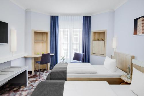 a hotel room with two beds and a desk at IntercityHotel Hamburg Altona in Hamburg