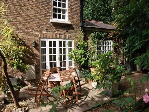 eine Terrasse mit Tisch und Stühlen vor einem Gebäude in der Unterkunft Garden Cottage in Twickenham