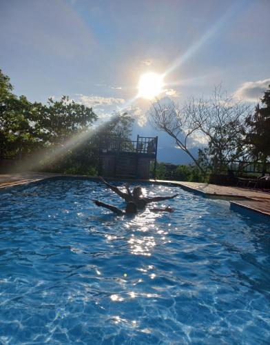 a person in a swimming pool with the sun in the background at San Rafael del Campo - Barichara in Barichara