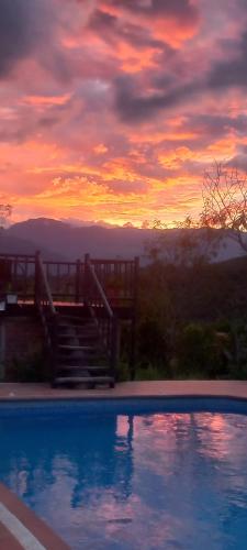 a swimming pool with a sunset in the background at San Rafael del Campo - Barichara in Barichara