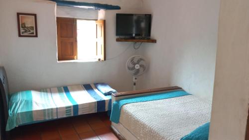 a bedroom with two beds and a window and a fan at San Rafael del Campo - Barichara in Barichara