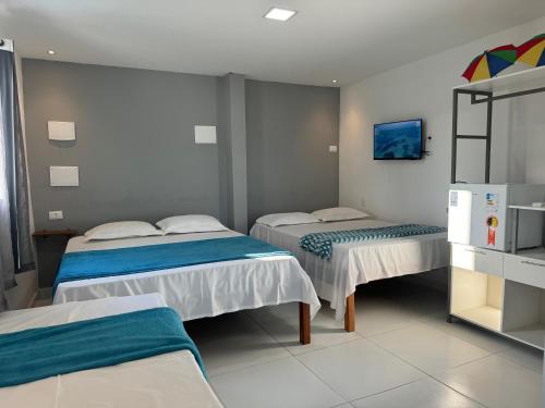 a hotel room with two beds and a refrigerator at Maraki Suítes Maragogi 150M do Mar in Maragogi