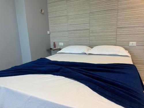 a bed with a blue blanket and two pillows at Maraki Suítes Maragogi 150M do Mar in Maragogi