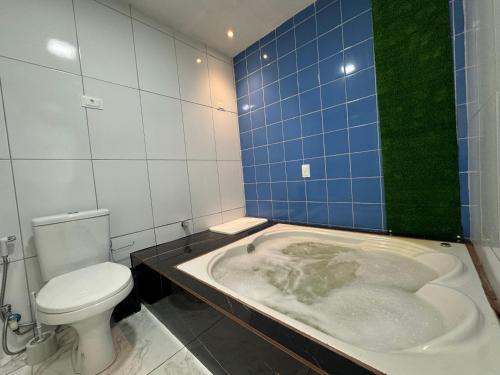 a bathroom with a bath tub with a toilet at Maraki Suítes Maragogi 150M do Mar in Maragogi