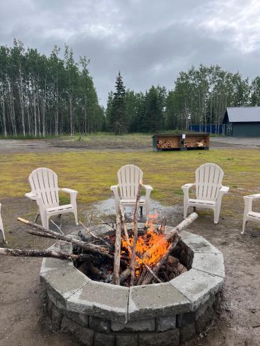 three chairs sitting around a fire in a yard at Kenai Adventure Cabins in Soldotna