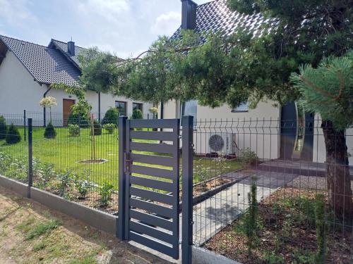a fence in front of a house with a tree at Willa Przygoda in Żukowo