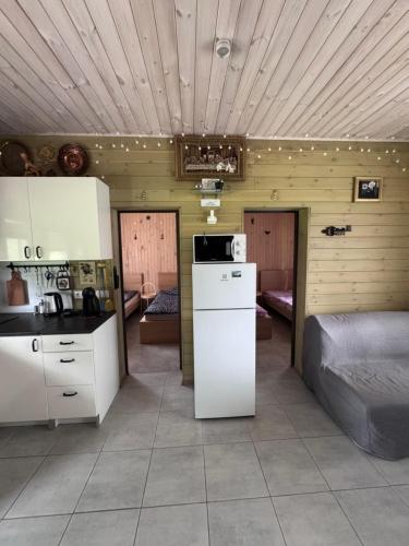 a kitchen with white cabinets and a bed in a room at Zvaigznītes in Aglona