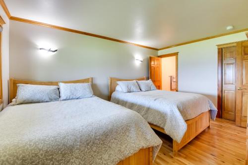 two beds in a bedroom with wooden floors at Pool Access Waterfront Lake Memphremagog Condo! in Newport
