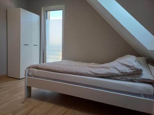 a white bedroom with a bed and a staircase at Willa Przygoda in Żukowo