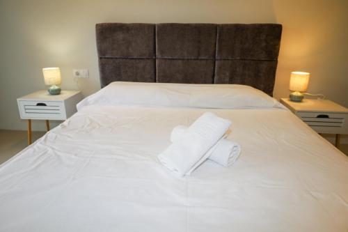 a white bed with two rolls of towels on it at ELAIA Αpartments in Alexandroupoli