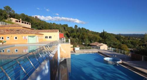 a large swimming pool with blue water in a house at Appartement dans Residence – Le Domaine de Camiole in Callian