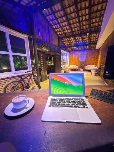 a laptop computer sitting on a table with a cup of coffee at Pousada Barra do Sahy in Barra do Sahy