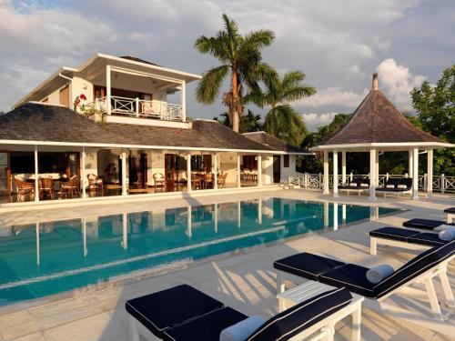 a villa with a swimming pool in front of a house at Round Hill Hotel & Villas in Montego Bay